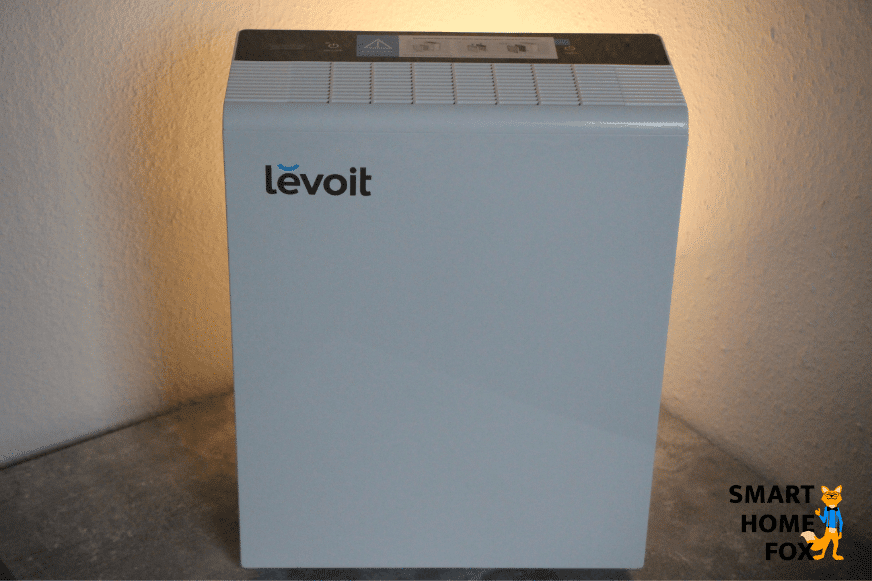 The Levoit LV-PUR131s air purifier stands on a table in front of a white wall.