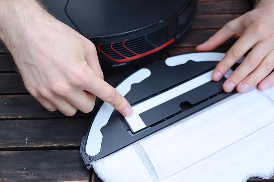 A finger points to the motor that provides the vibrating movements of the Roborock S7 MaxV's wiping plate. 