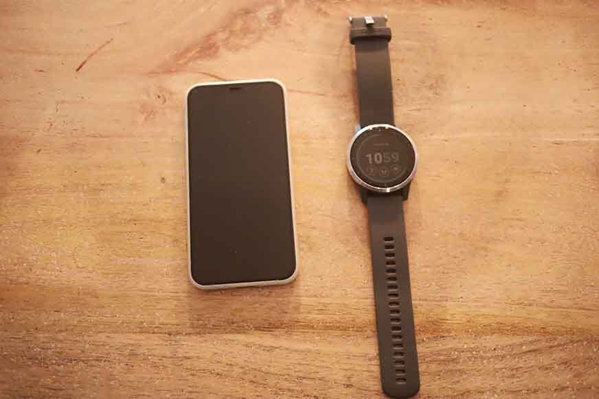 A smartwatch lying next to a mobile phone on the table.