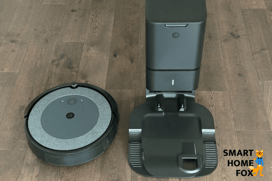 The iRobot Roomba i3 stands on the floor beside its self-emptying station.